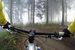 First person handlebar view of off-road biker on trail